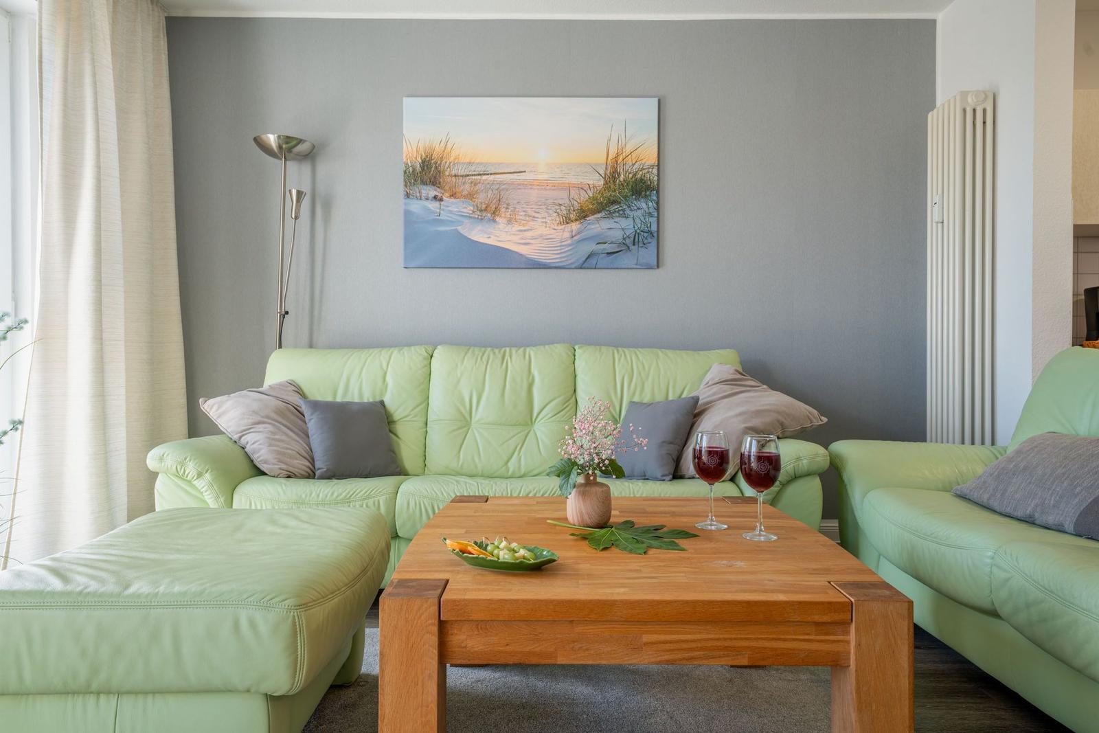 Ein Wohnzimmer mit grünen Sofas, einem Holztisch und einer Wanddekoration.