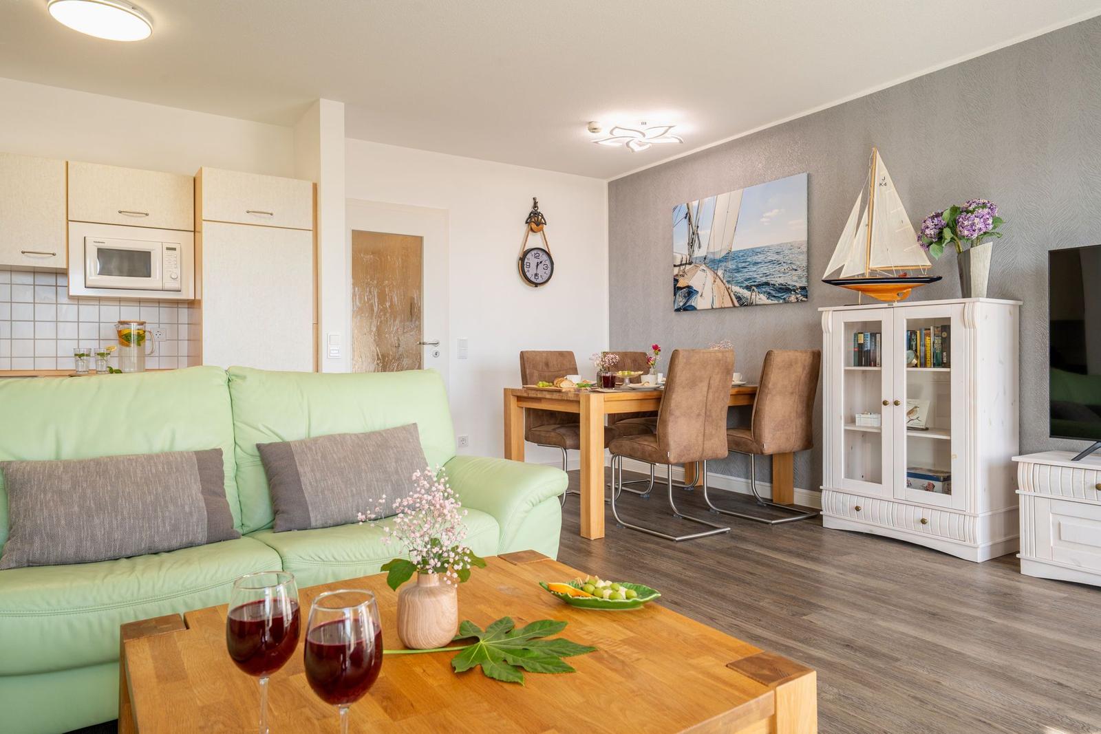 Wohn- und Essbereich mit Sofa, Esstisch und Küchenzeile.