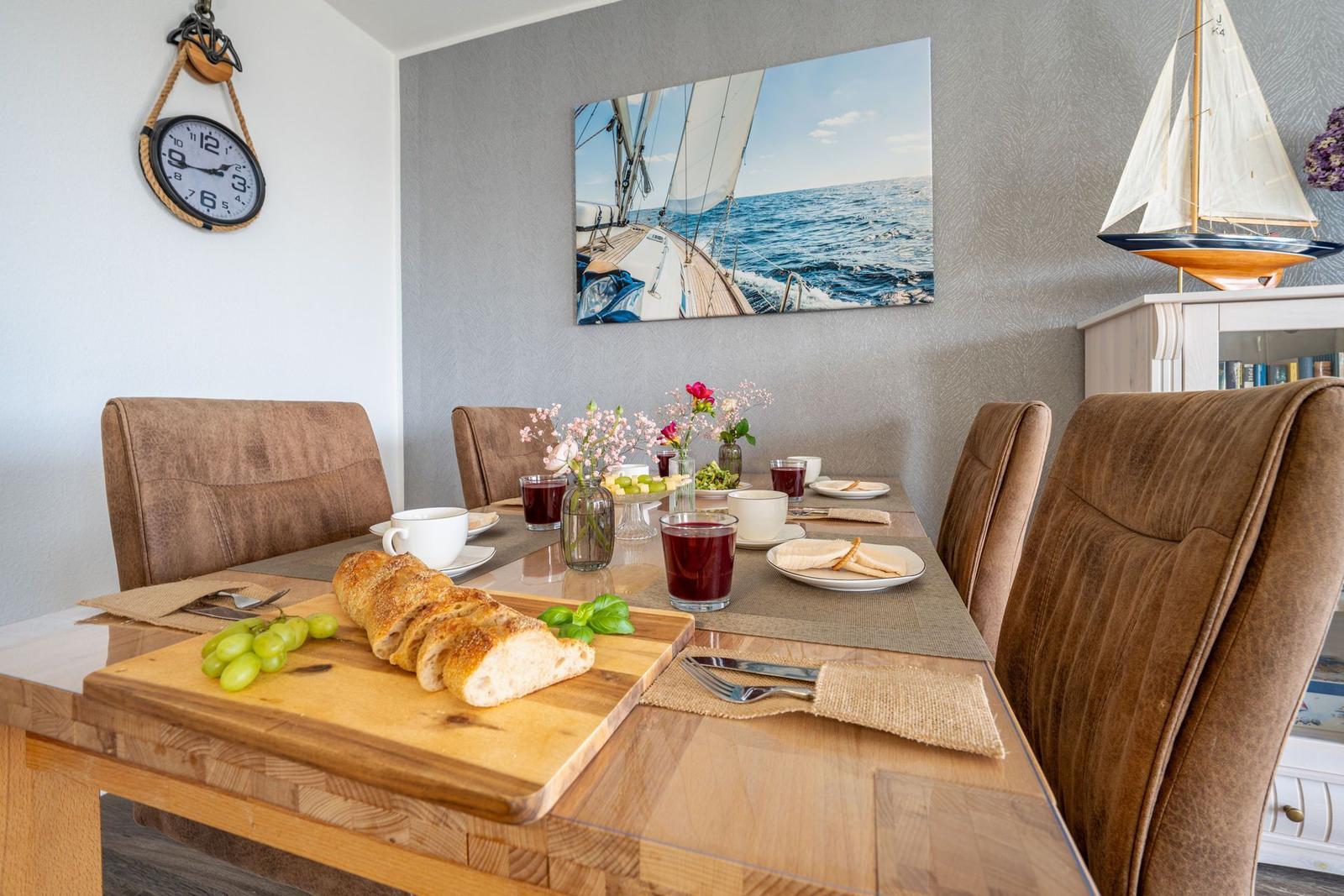 Esstisch mit Stühlen, Wandbild und Segelbootmodell