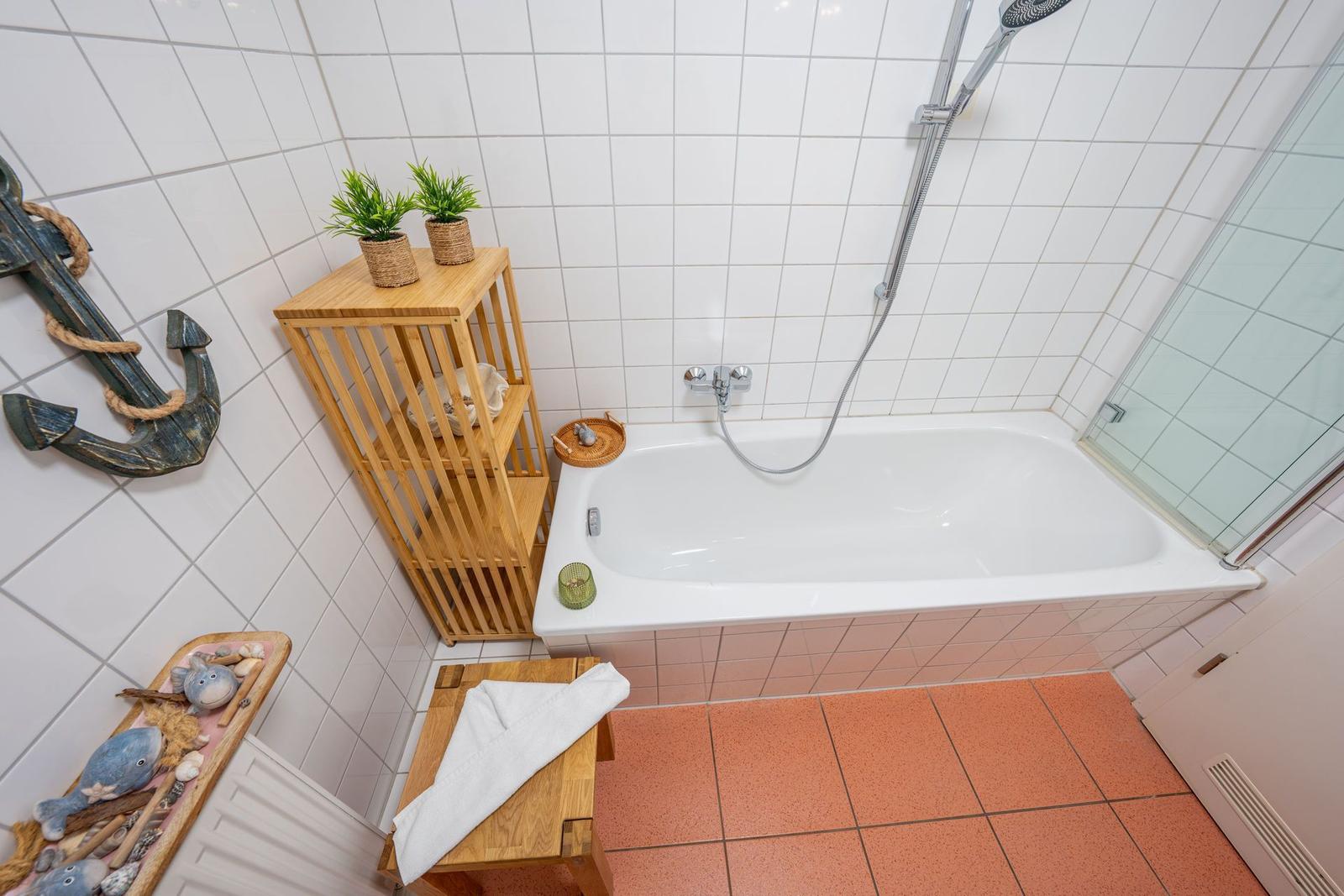 Bad mit Badewanne, Dusche und Holzregal mit Pflanzen.
