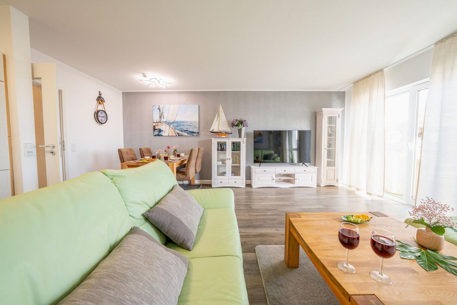 Wohn- und Essbereich mit Sofa, TV und Tisch. Blick auf Terrasse.