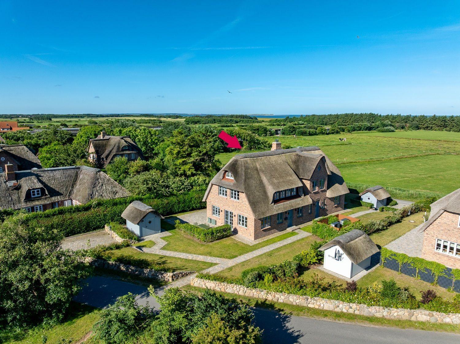 Dorfhaus mit Strohdach, Garten und Blick auf Felder und Meer.