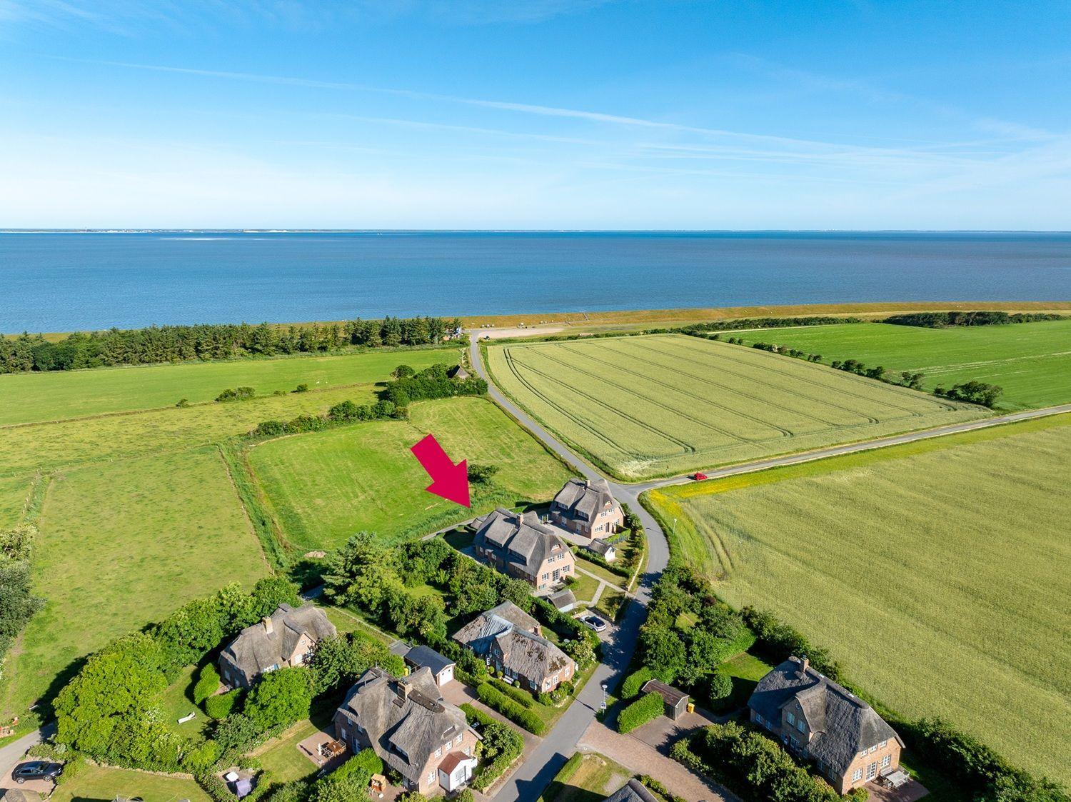 Haus mit Dach und Garten, umgeben von Feldern und Meer.