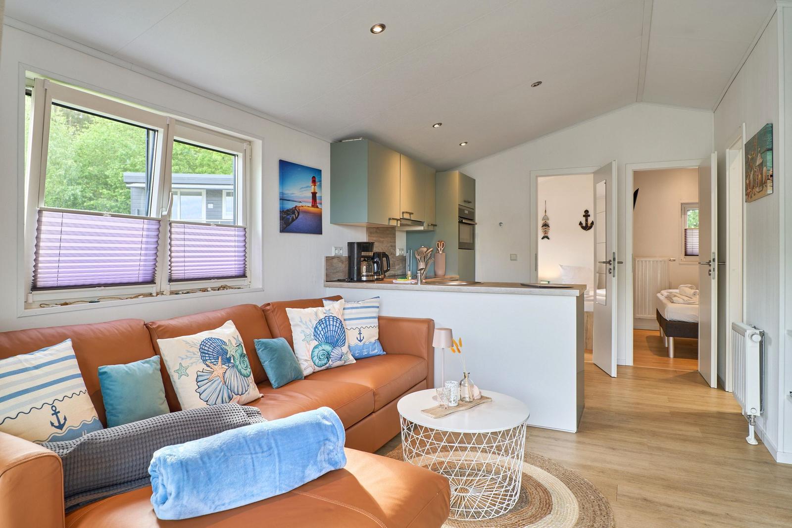 Wohnzimmer mit Sofa, Küchenbereich und Schlafzimmer im Hintergrund.