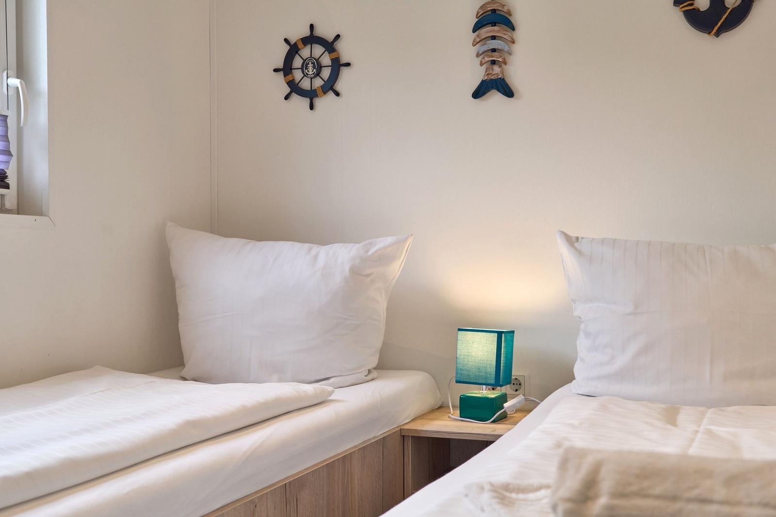 Zwei Betten mit weißen Bettwäsche, Nachttisch mit Lampe und Wanddekoration.