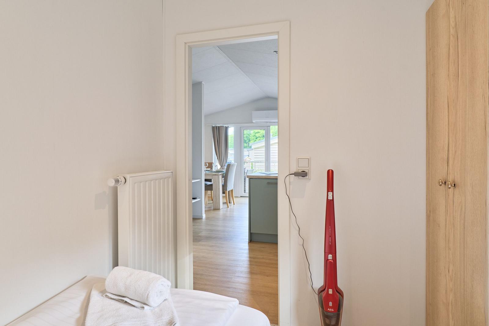 Schlafzimmer mit Blick in die Küche und Essnische. Roter Staubsauger an der Wand.
