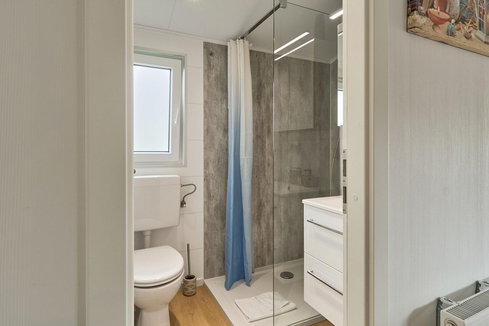 Badezimmer mit Dusche, Toilette und Waschbecken.