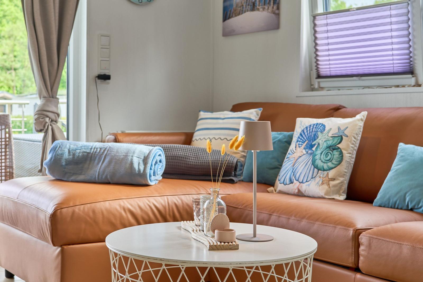 Ein Wohnzimmer mit braunem Sofa, Kissen und einem weißen Tisch.