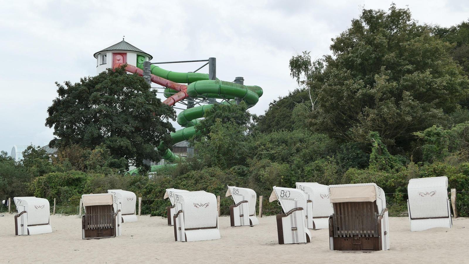 Strand mit Liegestühlen und Wasserrutsche im Hintergrund.