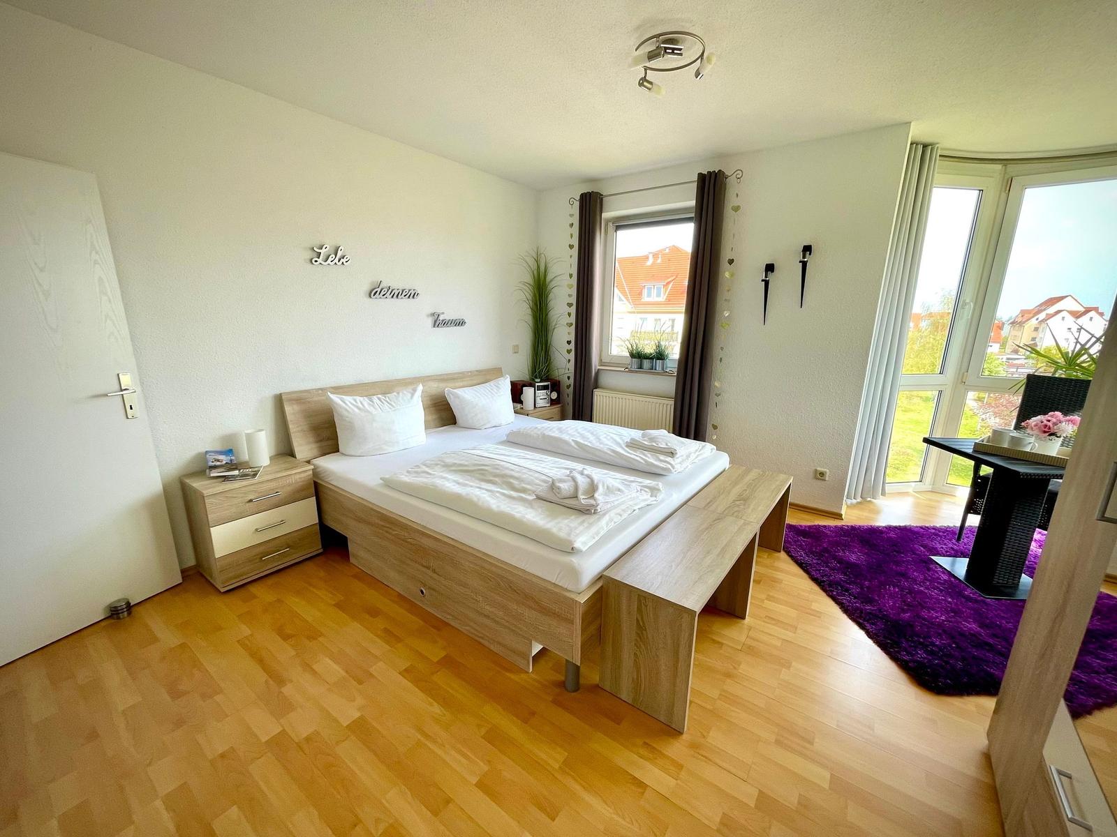 Schlafzimmer mit Doppelbett, Holzboden und Blick auf die Terrasse.
