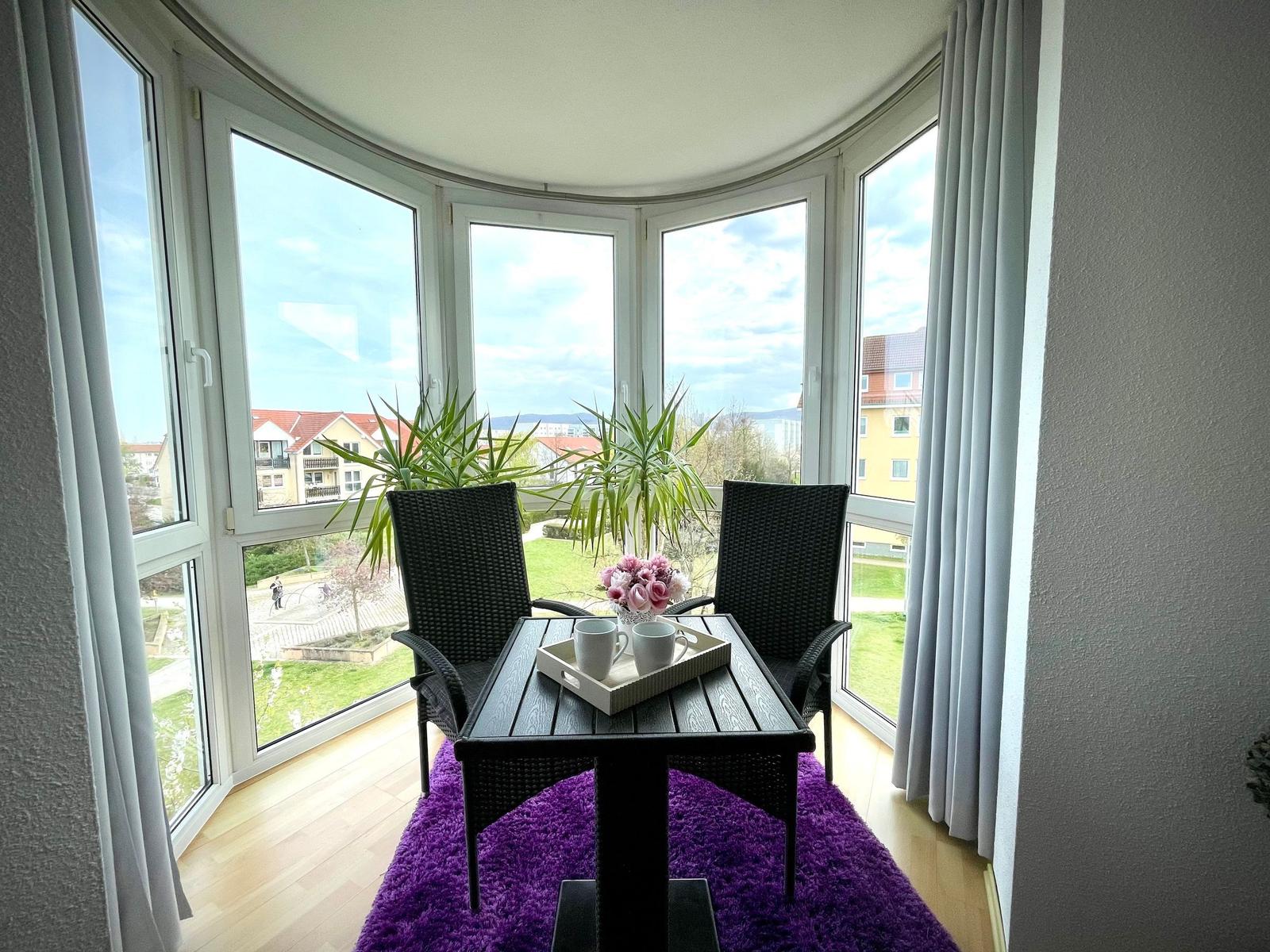 Balkon mit Tisch, zwei Stühlen und Blick auf Grünflächen.