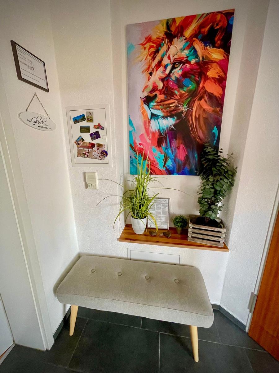 Eingangsbereich mit Sitzbank, Wandbild eines Löwen und Pflanzen.