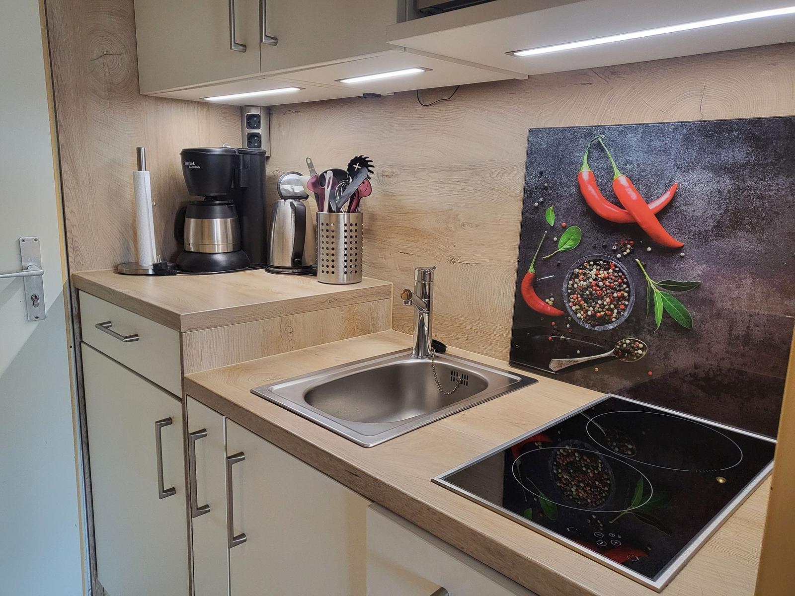 Kitchen with sink, cooktop, and worktop with wood finish.