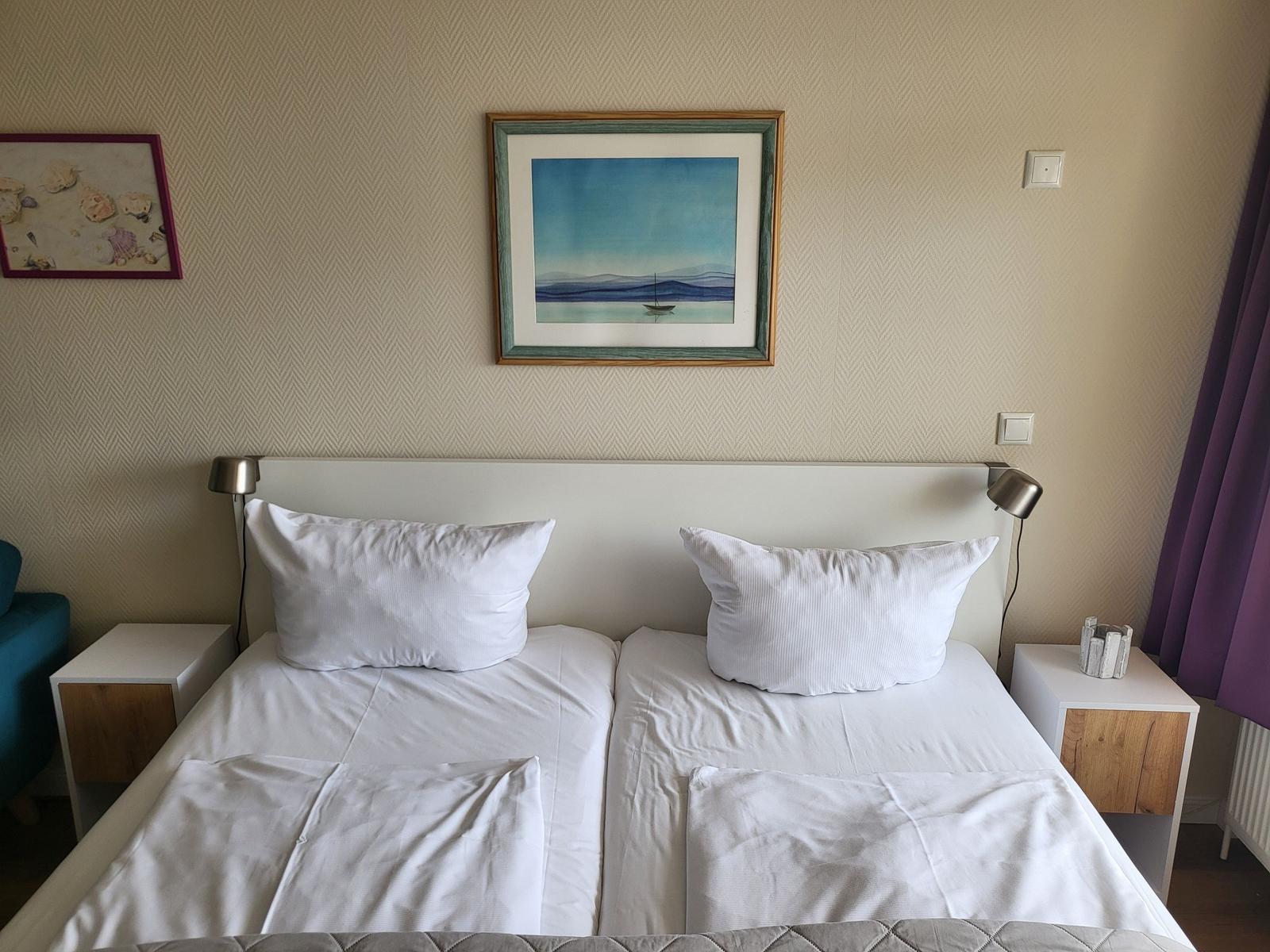 Double room with white linens, bedside tables, and wall art.