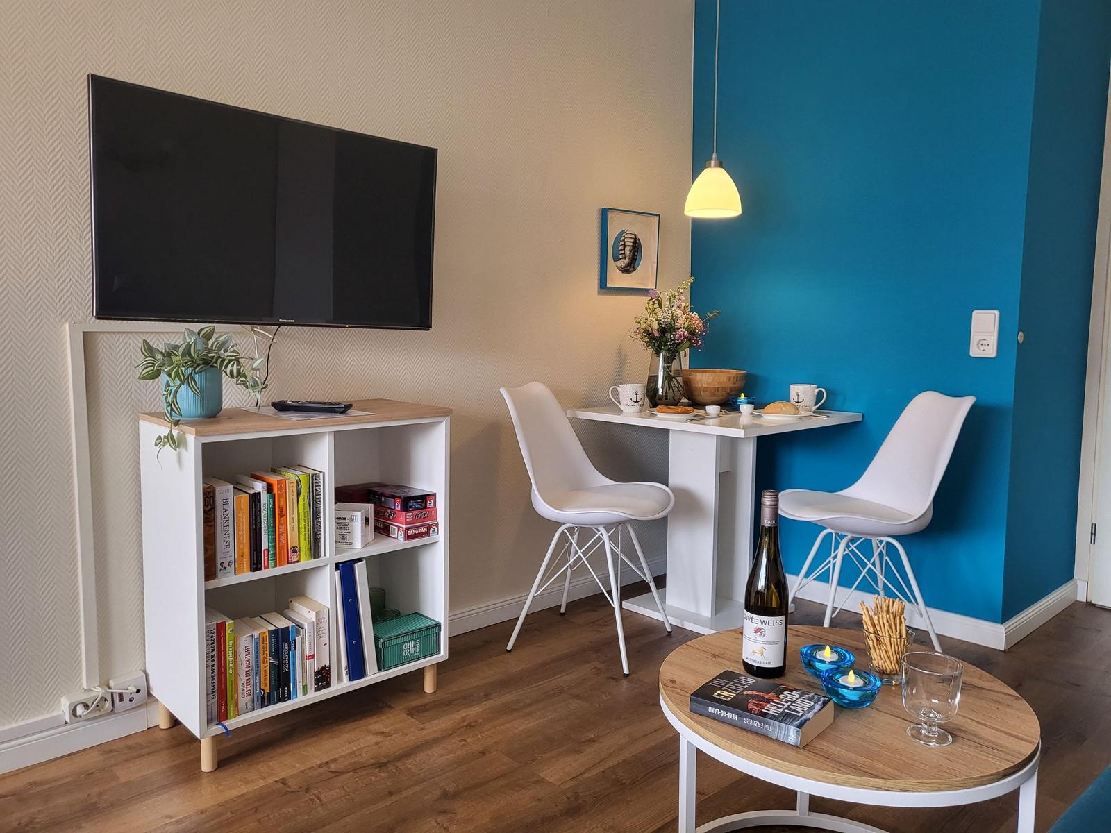 Living area with TV, bookshelf, dining table, and round coffee table.