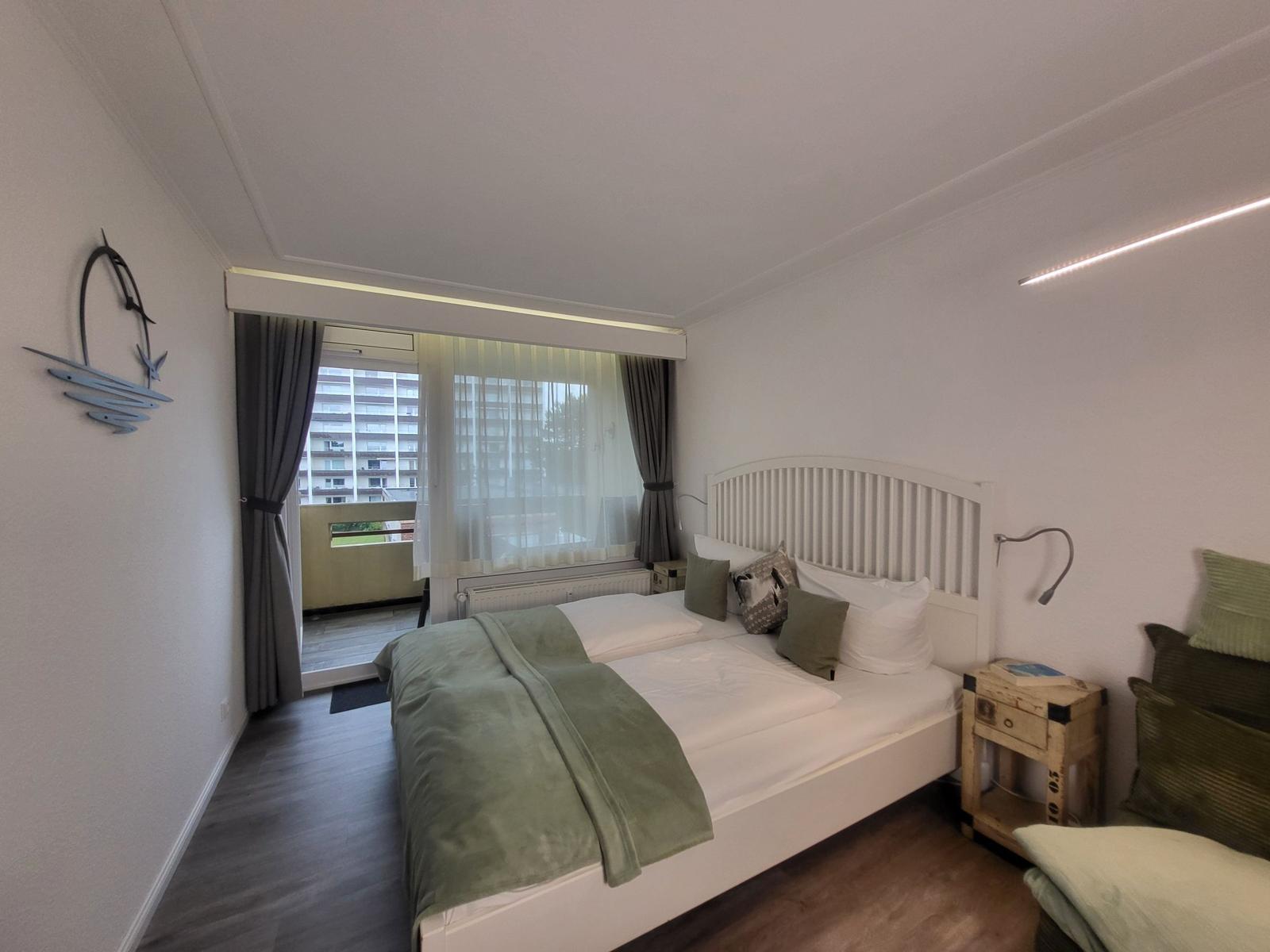 Schlafzimmer mit Doppelbett, Balkon und Nachttisch.