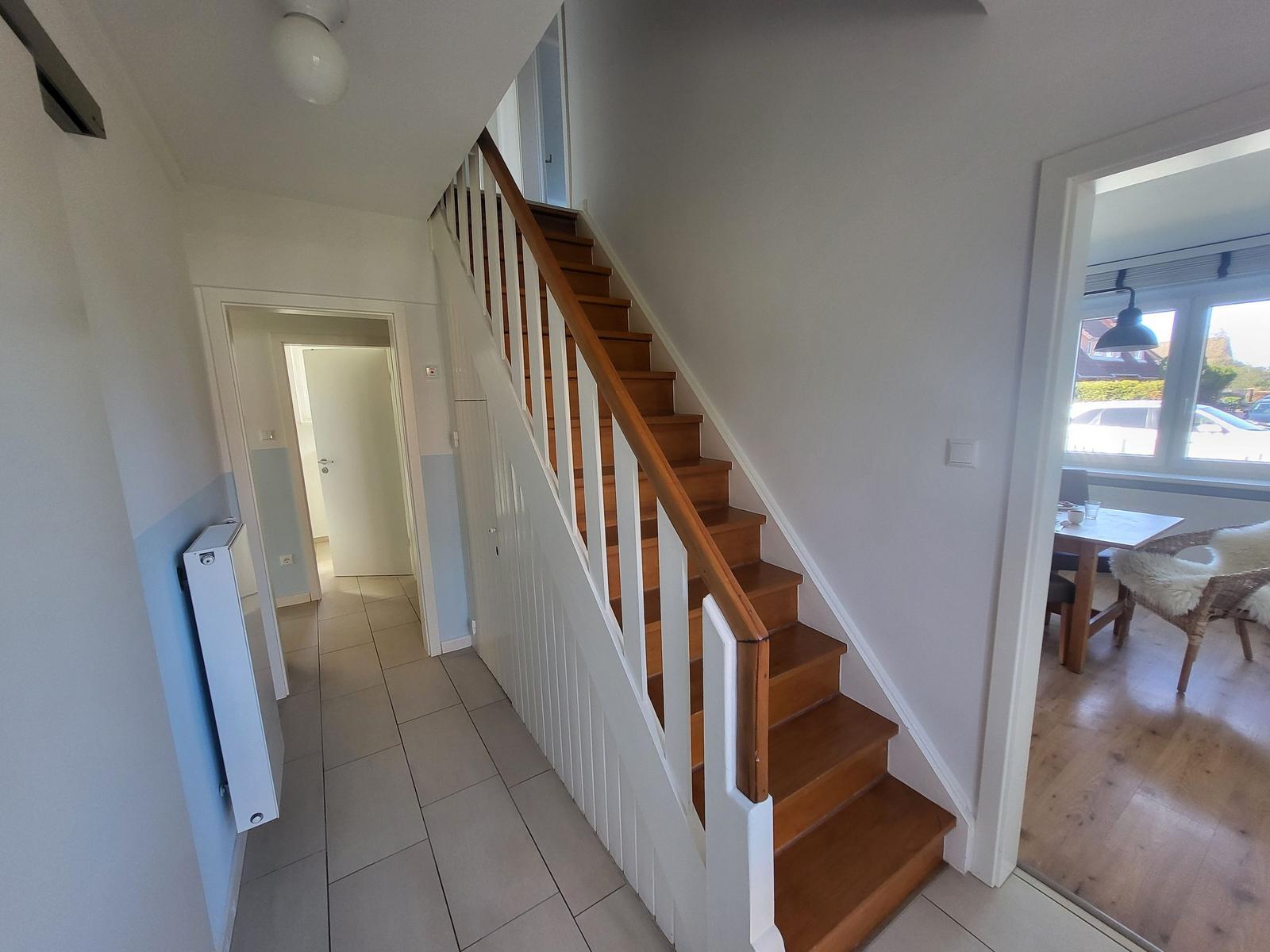 Staircase with wooden steps and white railings. Passage to living and sleeping areas.