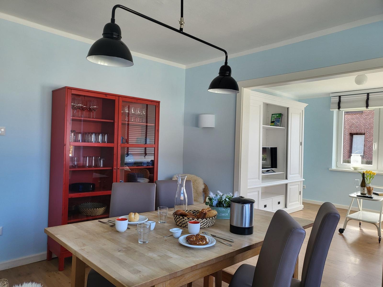Dining room with wooden table, red cabinet, and black pendant lights.