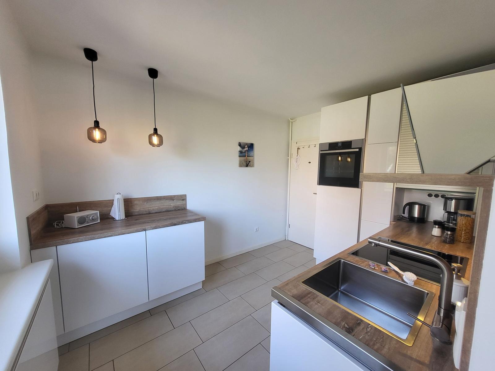 Kitchen with white cabinets, stainless steel sink, and built-in oven.