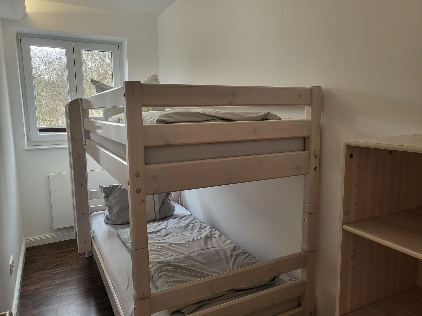 Zimmer mit Doppelstockbett, Fenster und Holzregal