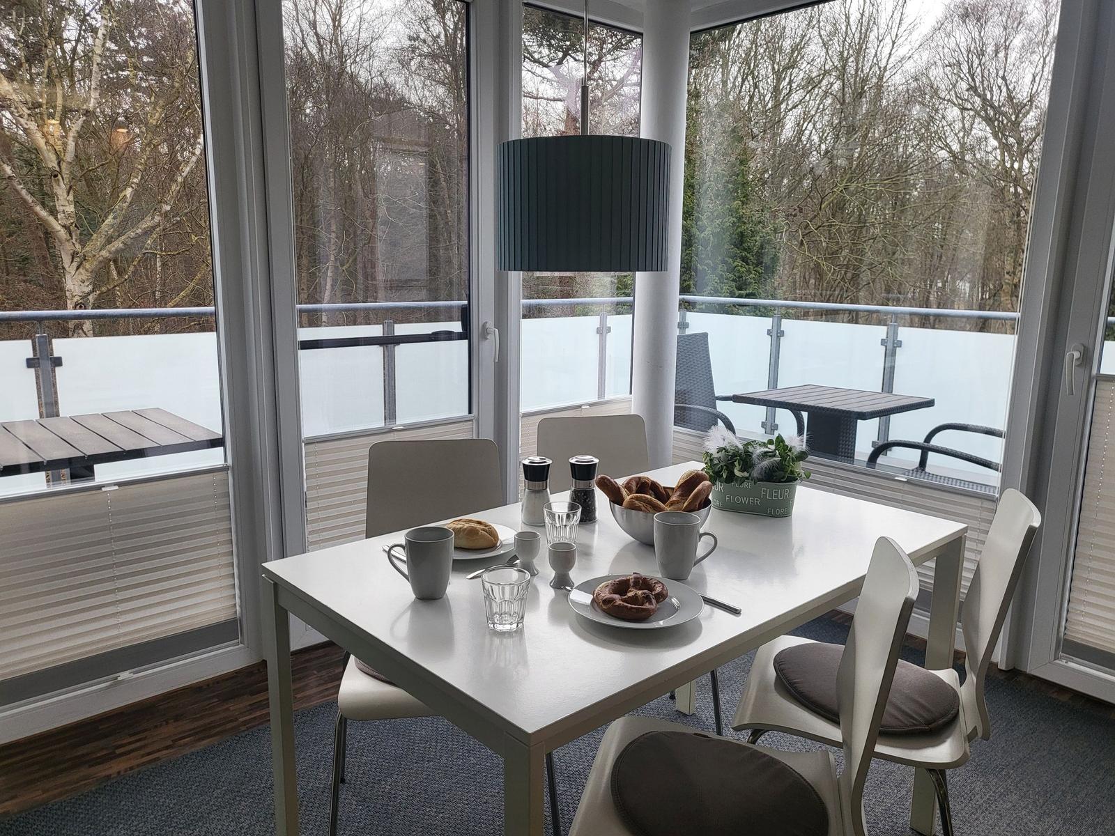 Esszimmer mit Tisch, Stühlen und Blick auf Balkon mit Sitzgelegenheit.