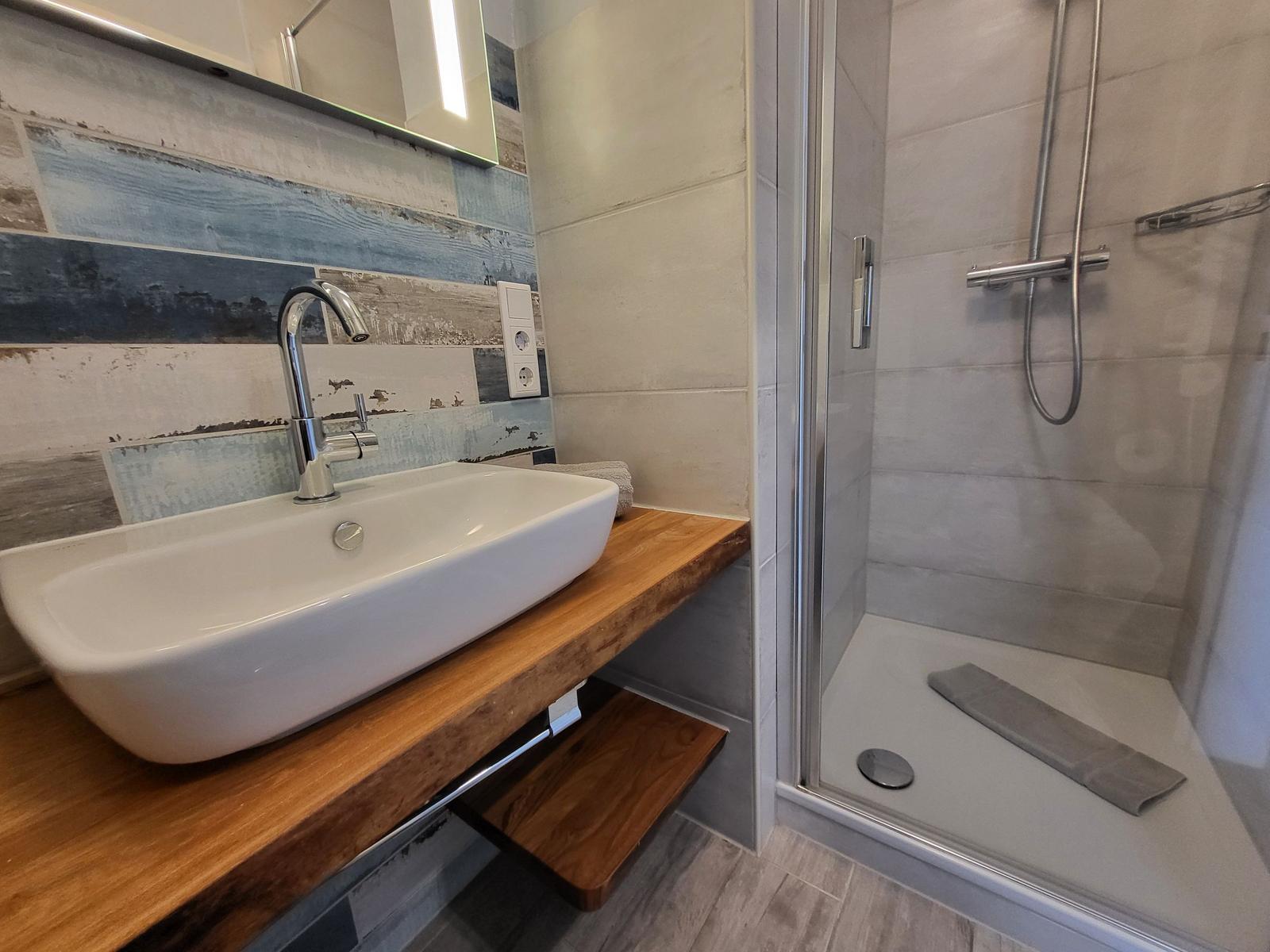 Bad mit Dusche und Waschbecken auf Holzkonsole