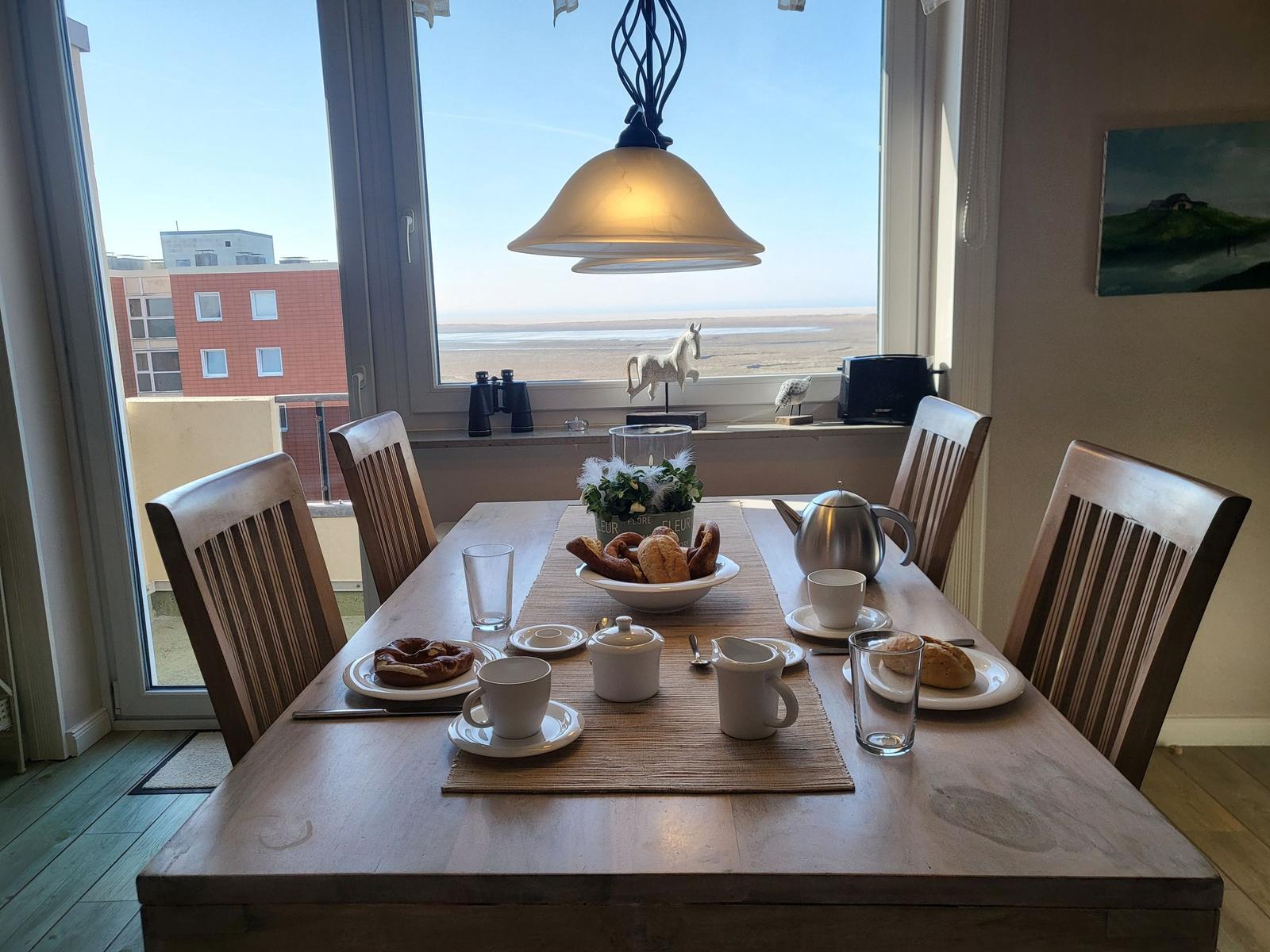 Esstisch mit Frühstück und Blick auf Strand und Himmel.