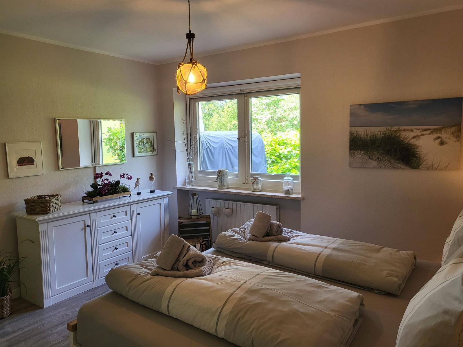 Zwei Betten mit Bettwäsche, Schrank, Fenster und Wandbild.