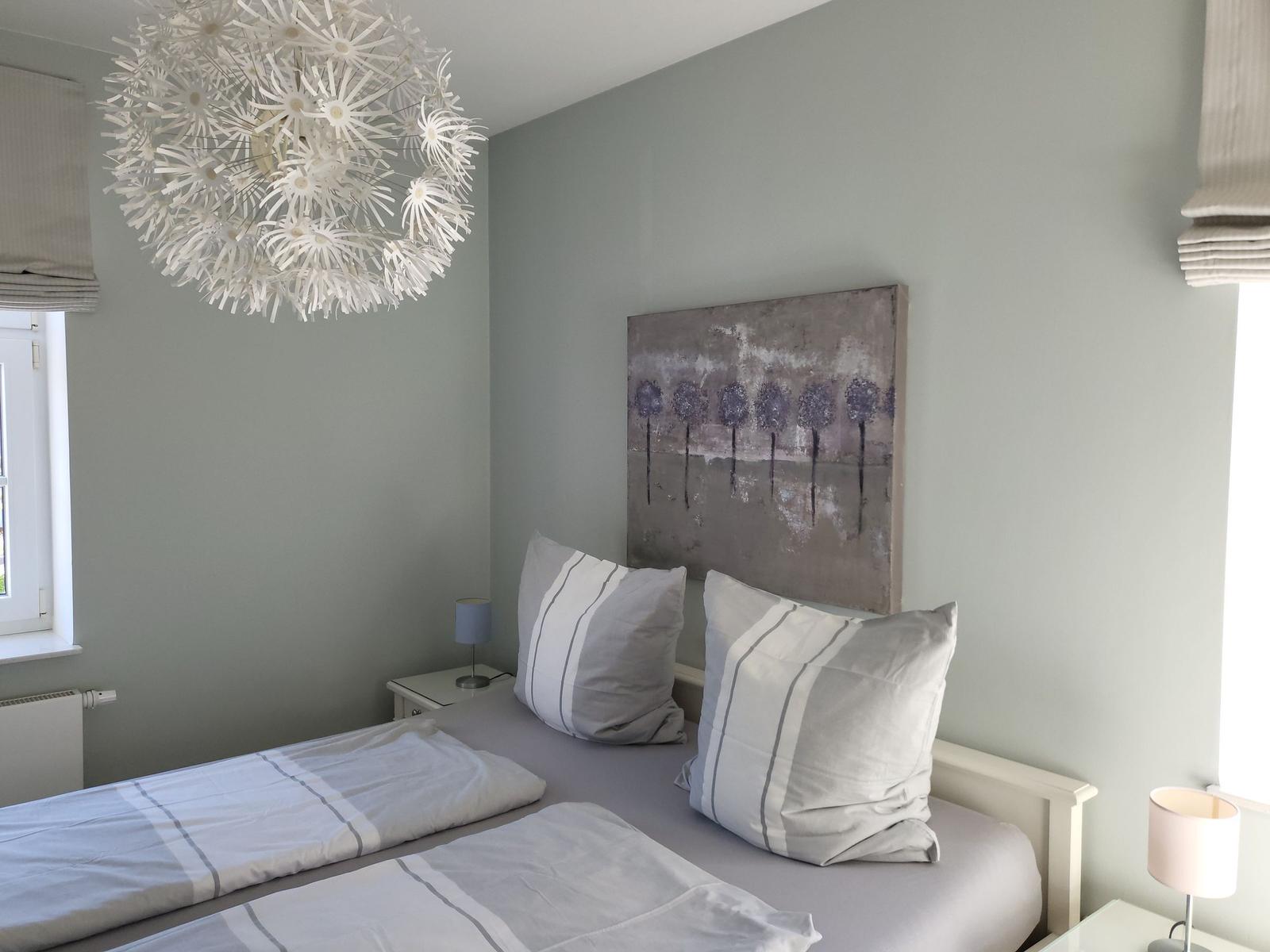 Schlafzimmer mit Bett, Nachttisch und Wandbild. Decke mit Dolden-Form.