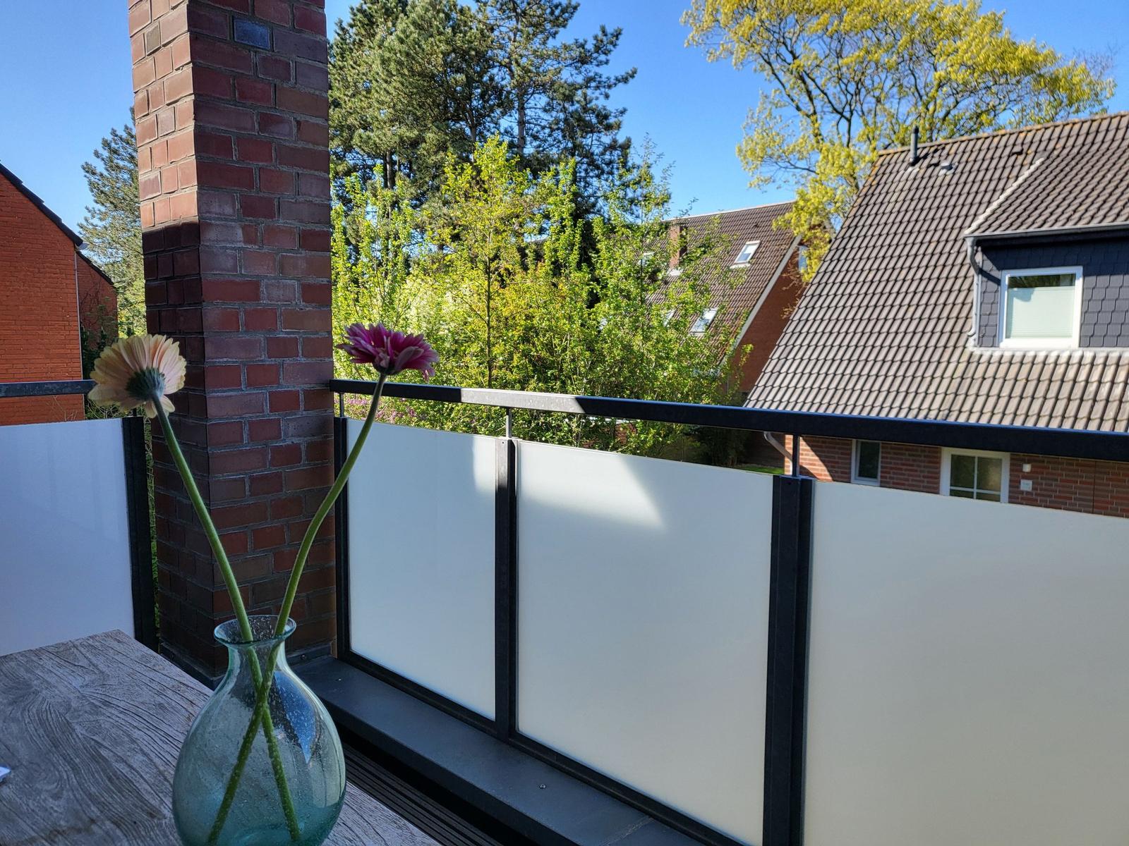 Terrasse mit Blumen und Blick auf Häuser und Bäume.