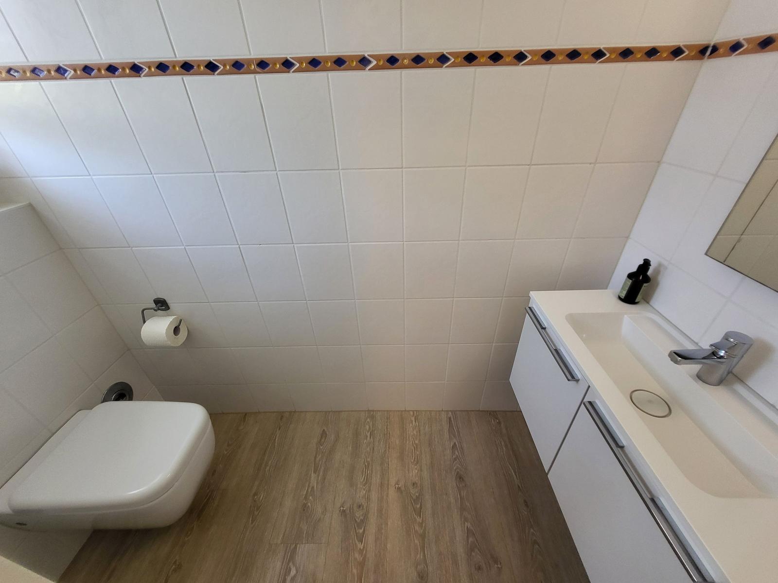 Badezimmer mit Toilette, Waschbecken und Holzdielenboden