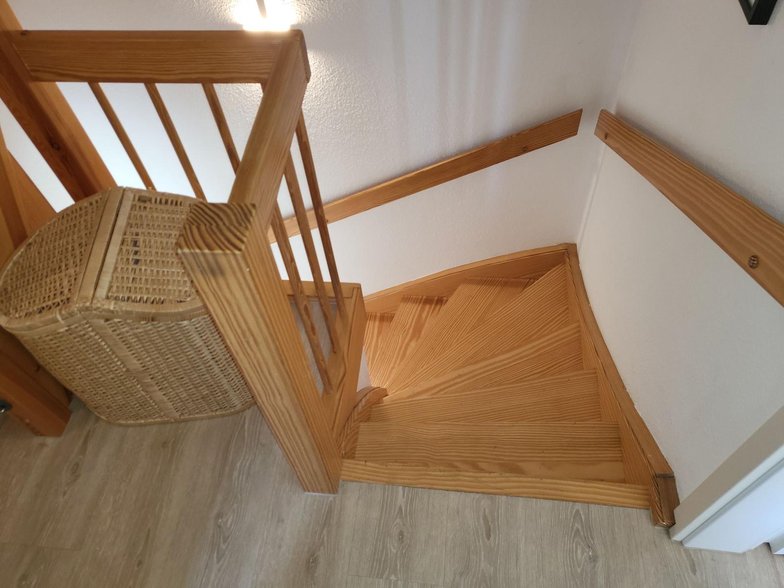 Holztreppe mit Geländer und Wickerkorb an der Wand.