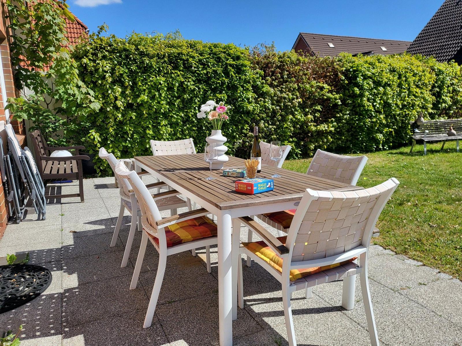 Hinterhof mit Tisch und Stühlen, Blumen und Weinflasche auf Tisch