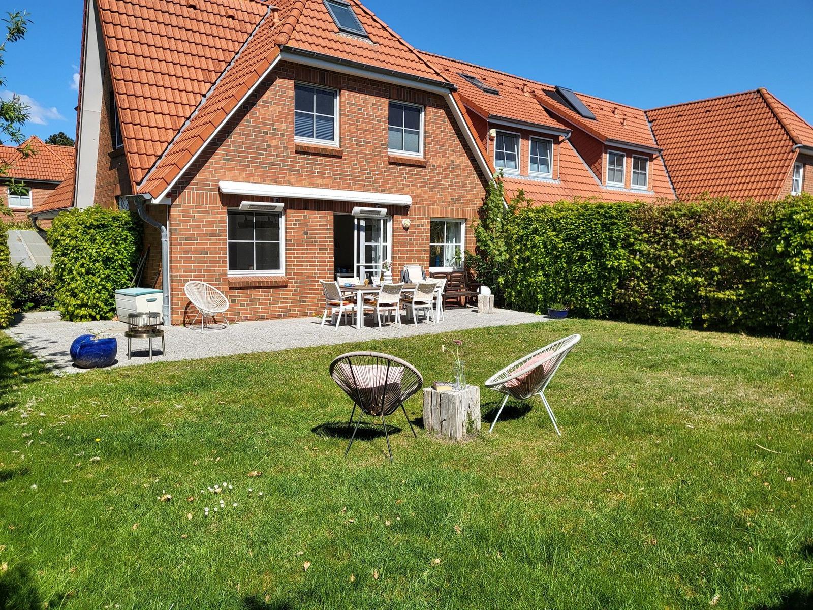 Rotes Ziegeldach, gemauerter Gartenbereich mit Tisch, Stühlen und Sitzgelegenheiten.
