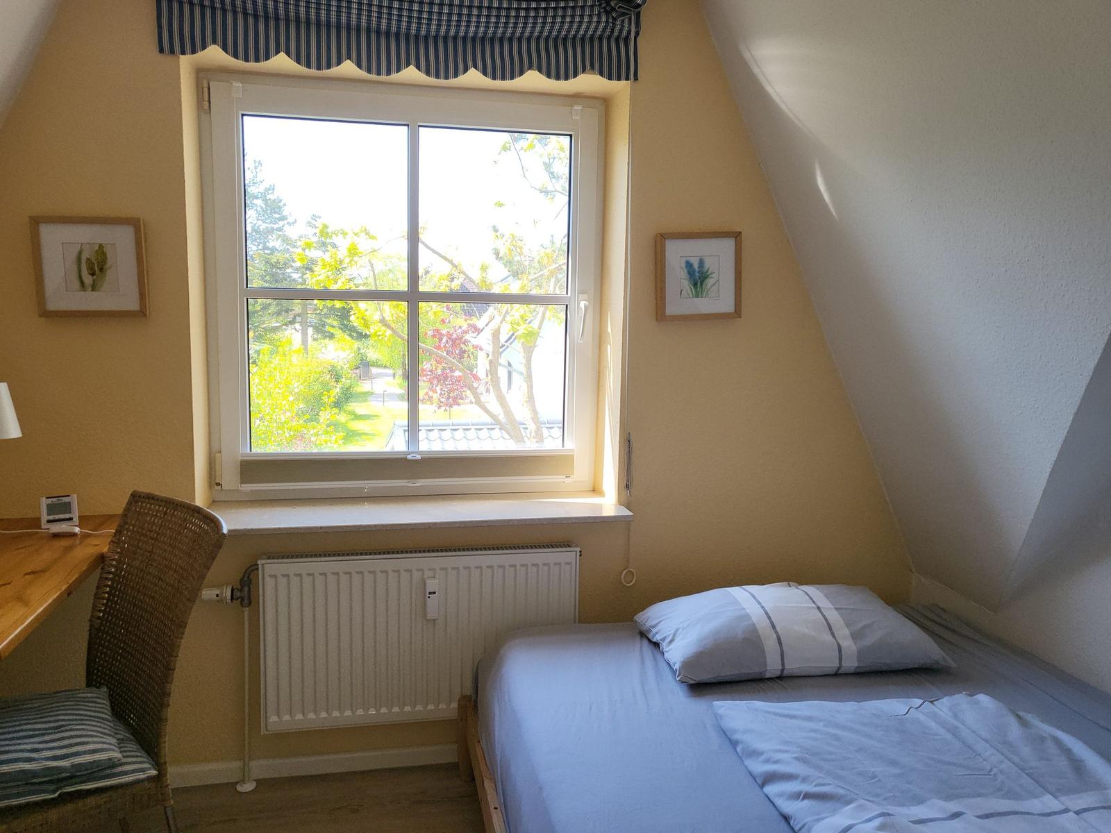 Schlafzimmer mit Dachschrägen, Fenster und Bett.