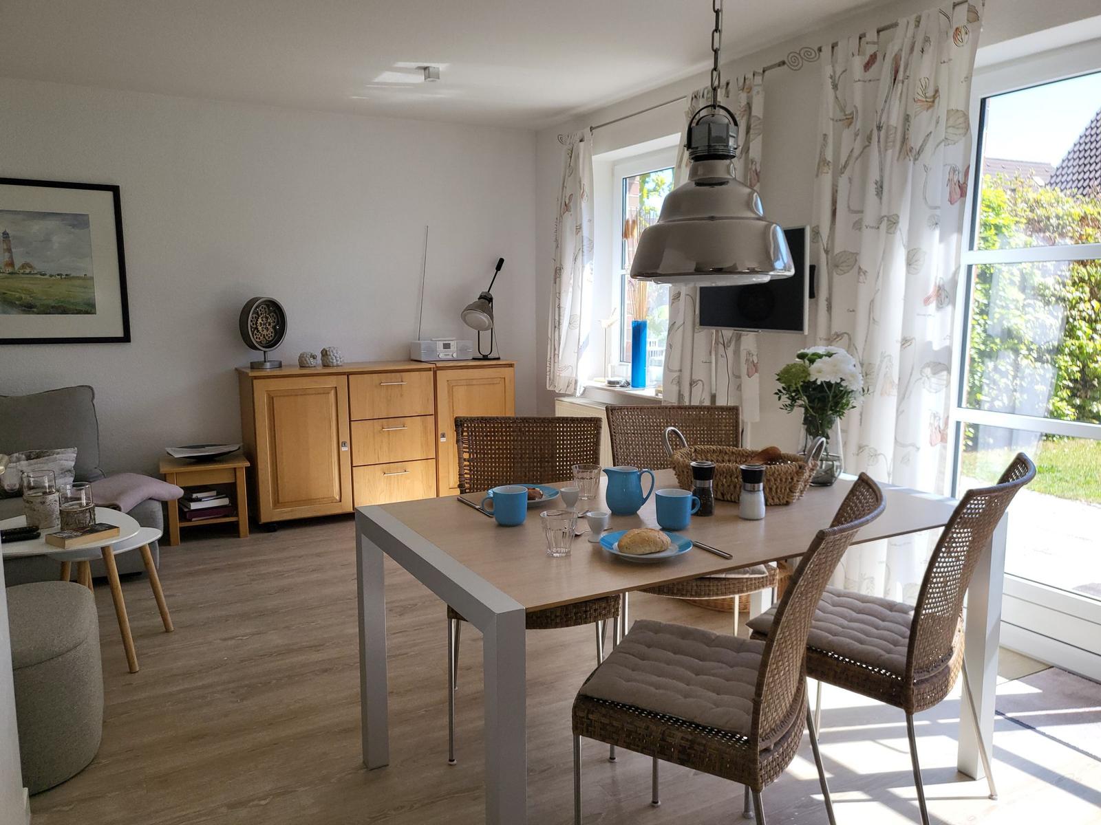 Esszimmer mit Esstisch, Stühlen und Fenster. Hängelampe und TV an der Wand.