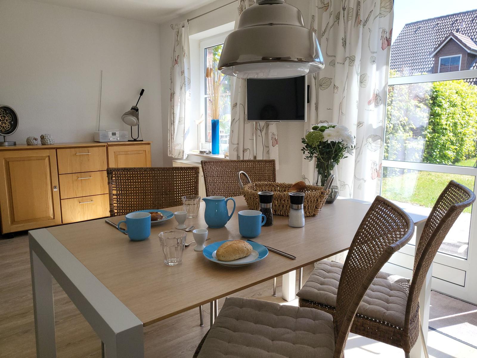 Esstisch mit Stühlen, Fenster und TV an der Wand