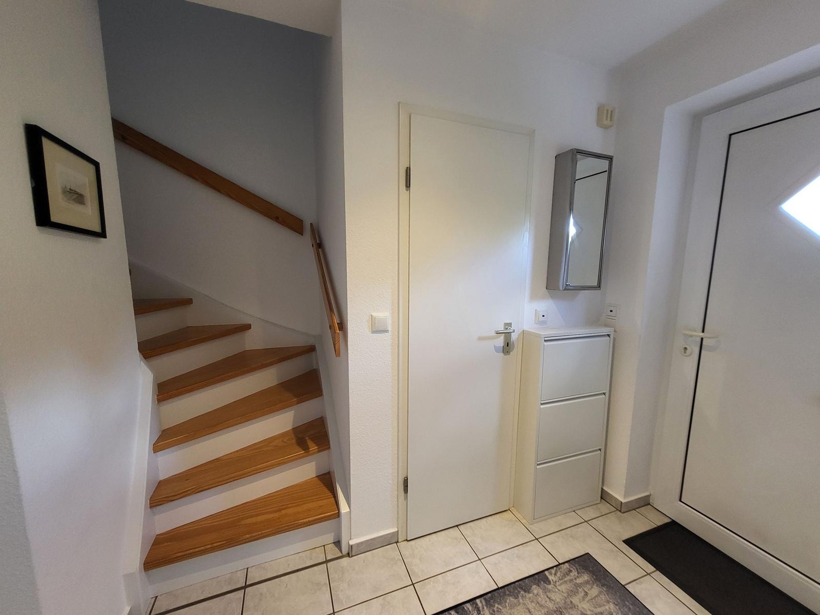 Eingangsbereich mit Treppe, Schrank und Tür.