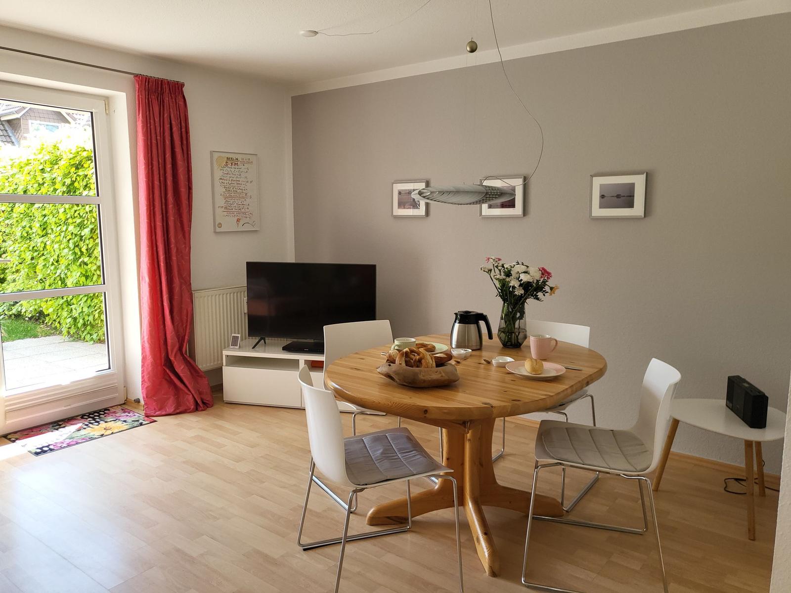 Esszimmer mit runden Tisch, weißen Stühlen und Fenster zur Außenseite.