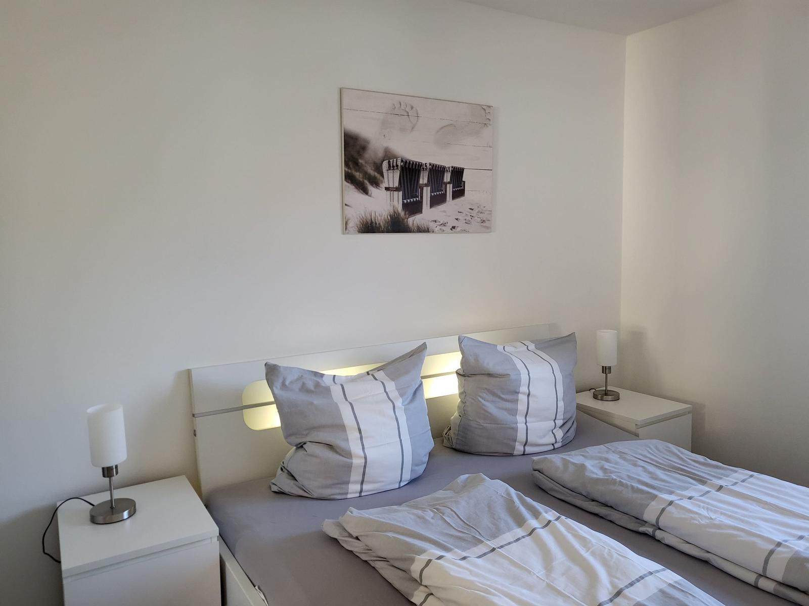 Ein Schlafzimmer mit Bett, zwei Nachttischen und einer Wanddekoration.