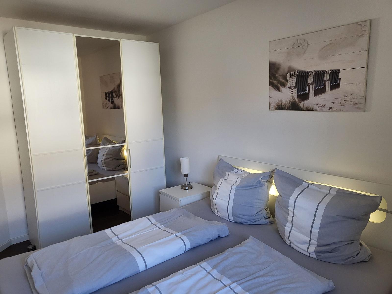 Schlafzimmer mit Doppelbett, Schrank und Wandbild