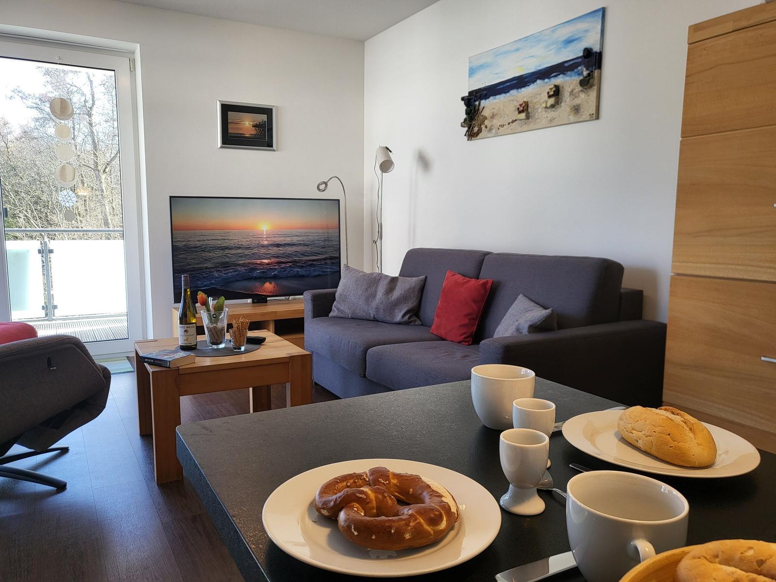 Wohnzimmer mit Sofa, Fernseher und Frühstückstablett.