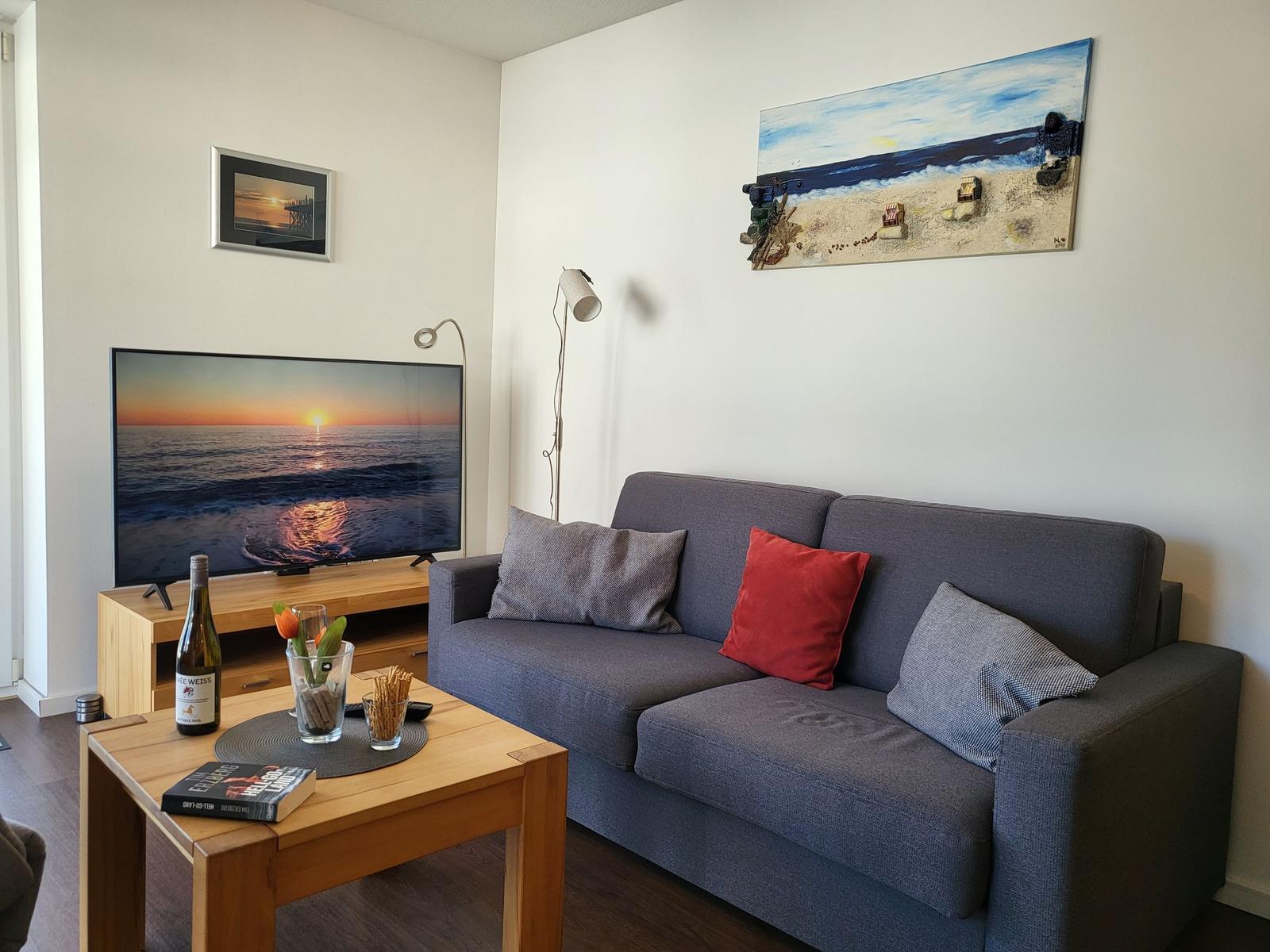 Ein Wohnzimmer mit Sofa, Fernseher und Tisch mit Getränken.
