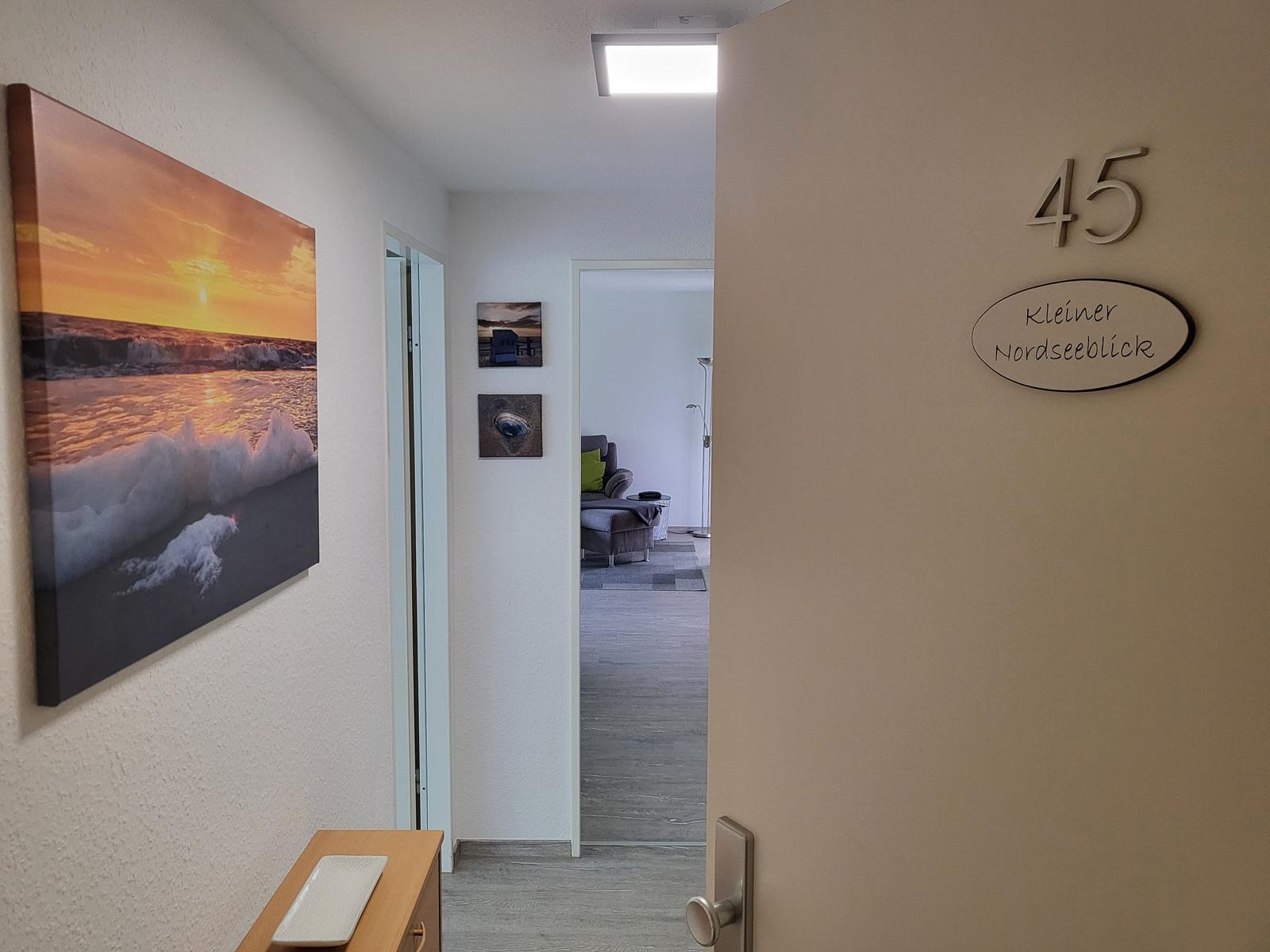 Eingangsbereich mit Wandbild und Schild 45 Kleiner Nordseeblick. Durchgang zur Wohnfläche.