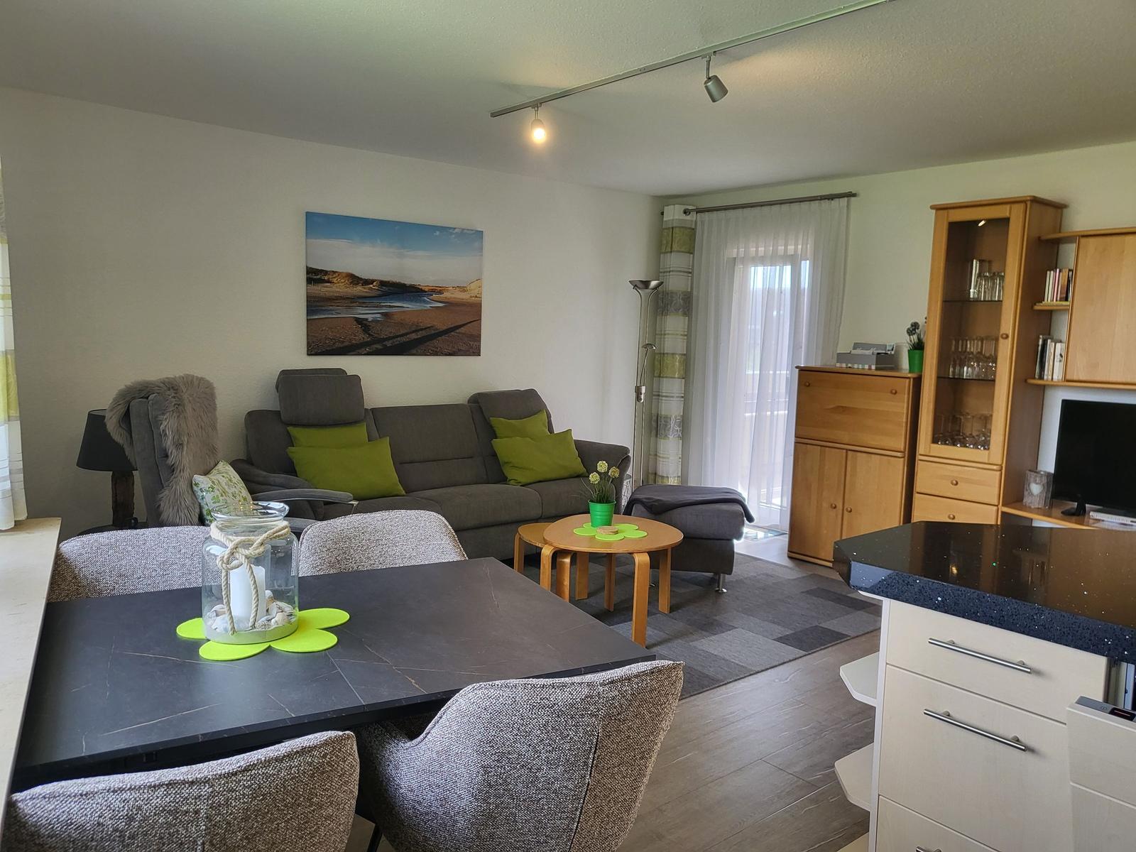 Wohn- und Essbereich mit Sofa, Tisch und Küchenzeile.