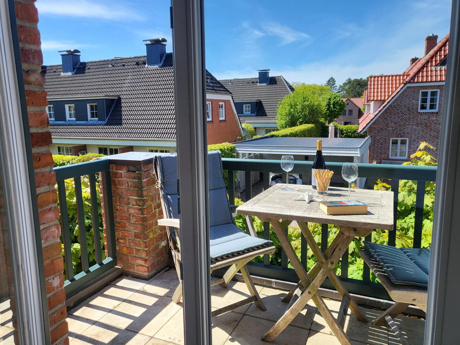 Terrasse mit Tisch, Stühlen und Blick auf Häuser und Grün.