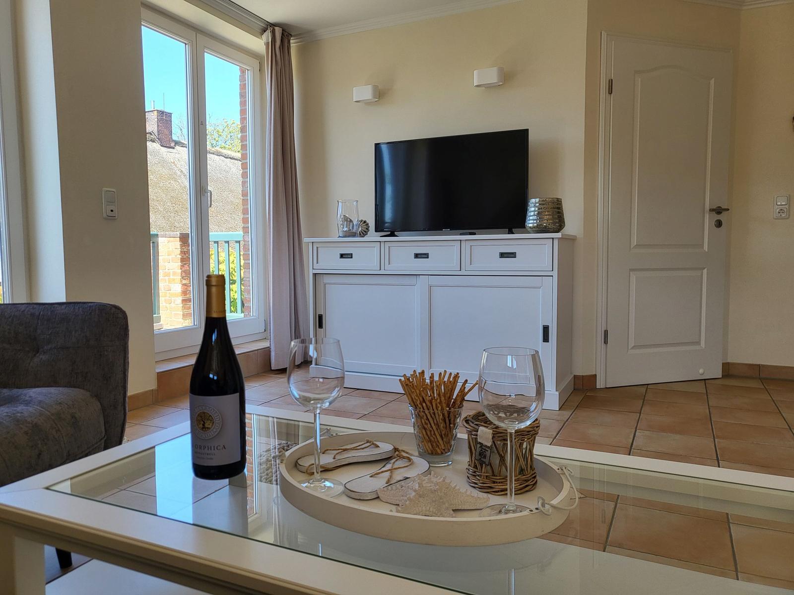 Wohnzimmer mit TV, Glas-Tisch und Blick auf Balkon