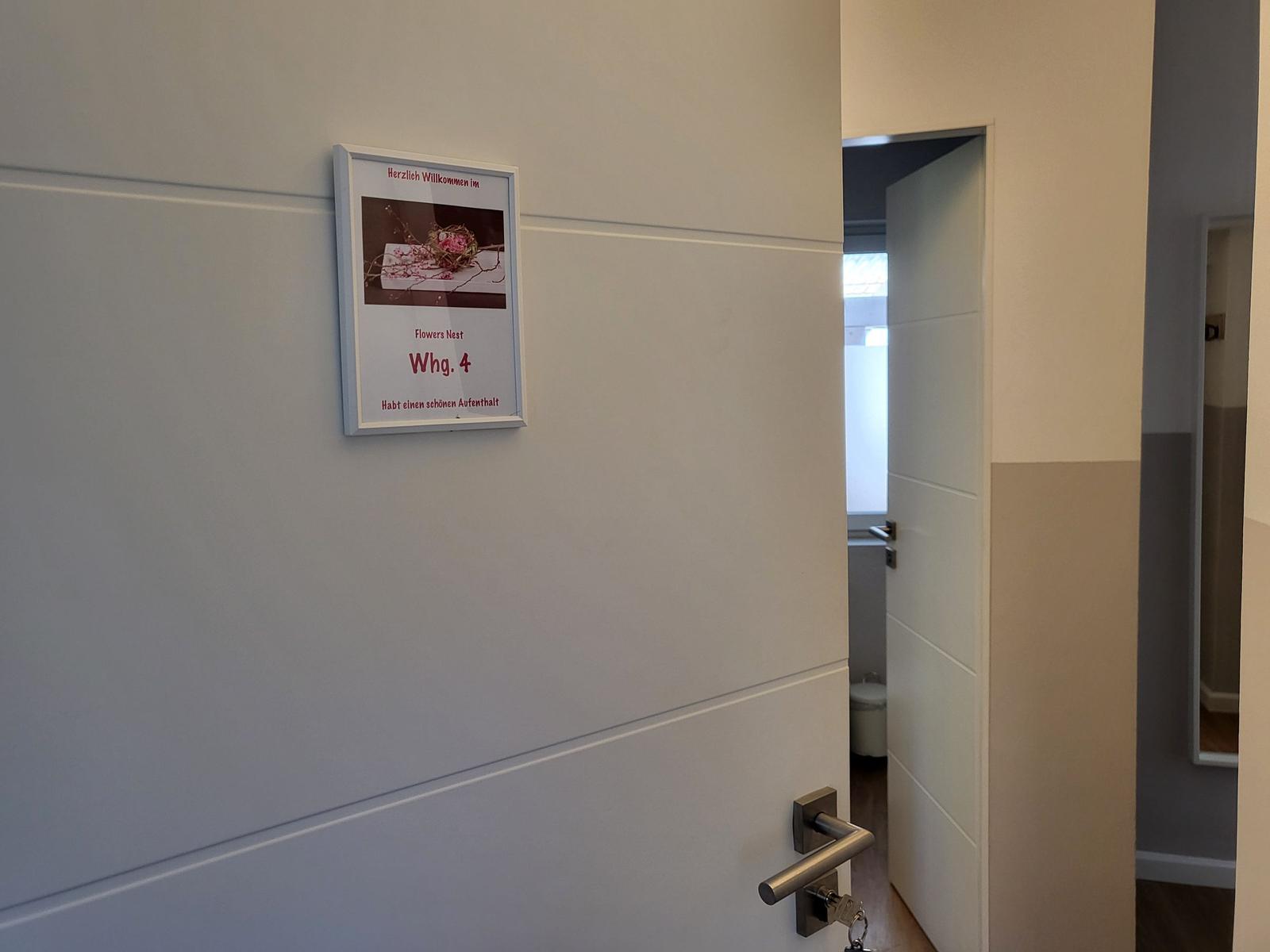 Willkommensschild an der Tür zur Wohnung 4 mit Schlüssel