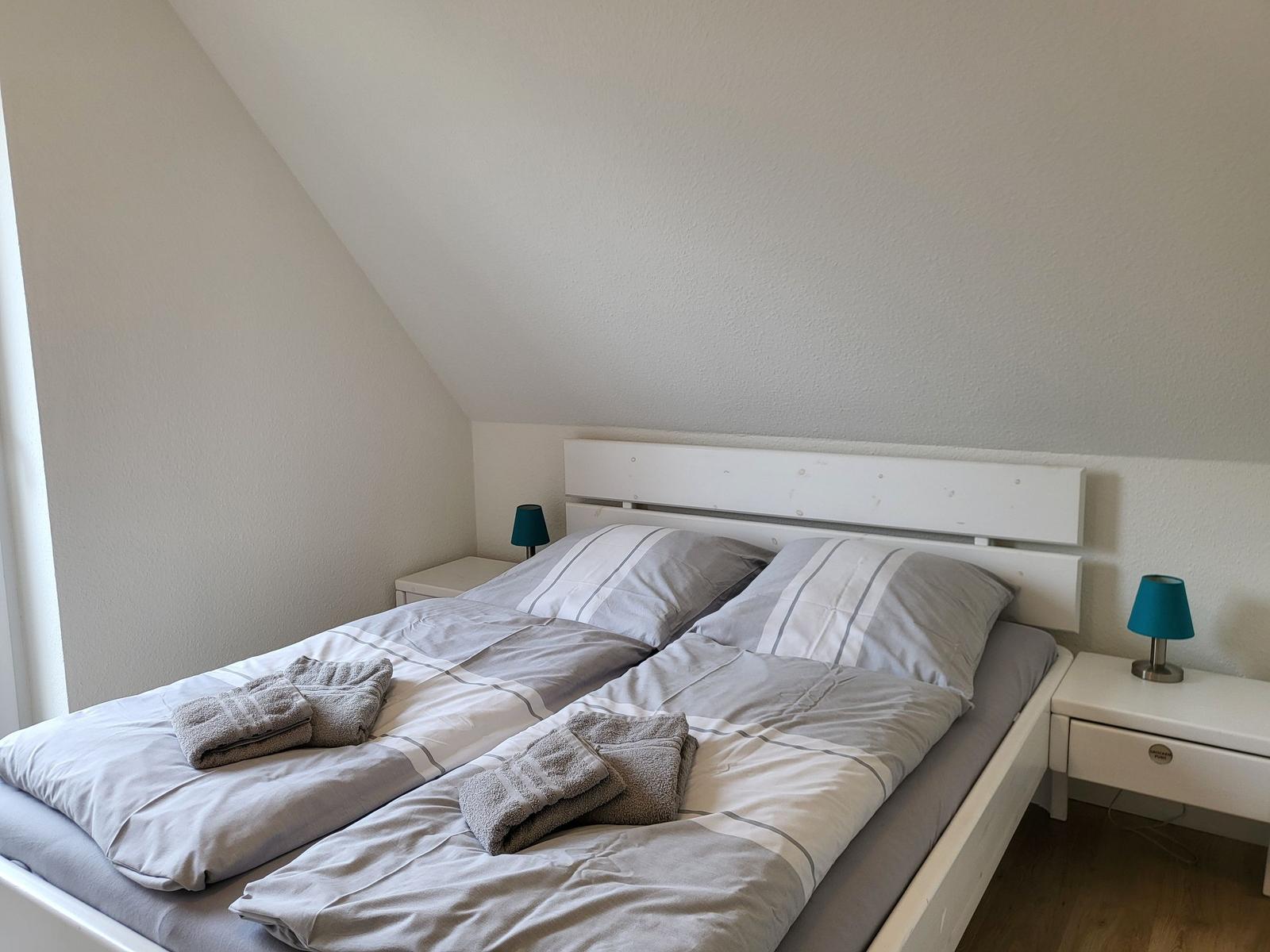 Schlafzimmer mit Doppelbett, zwei Nachttischen und blauen Lampen.