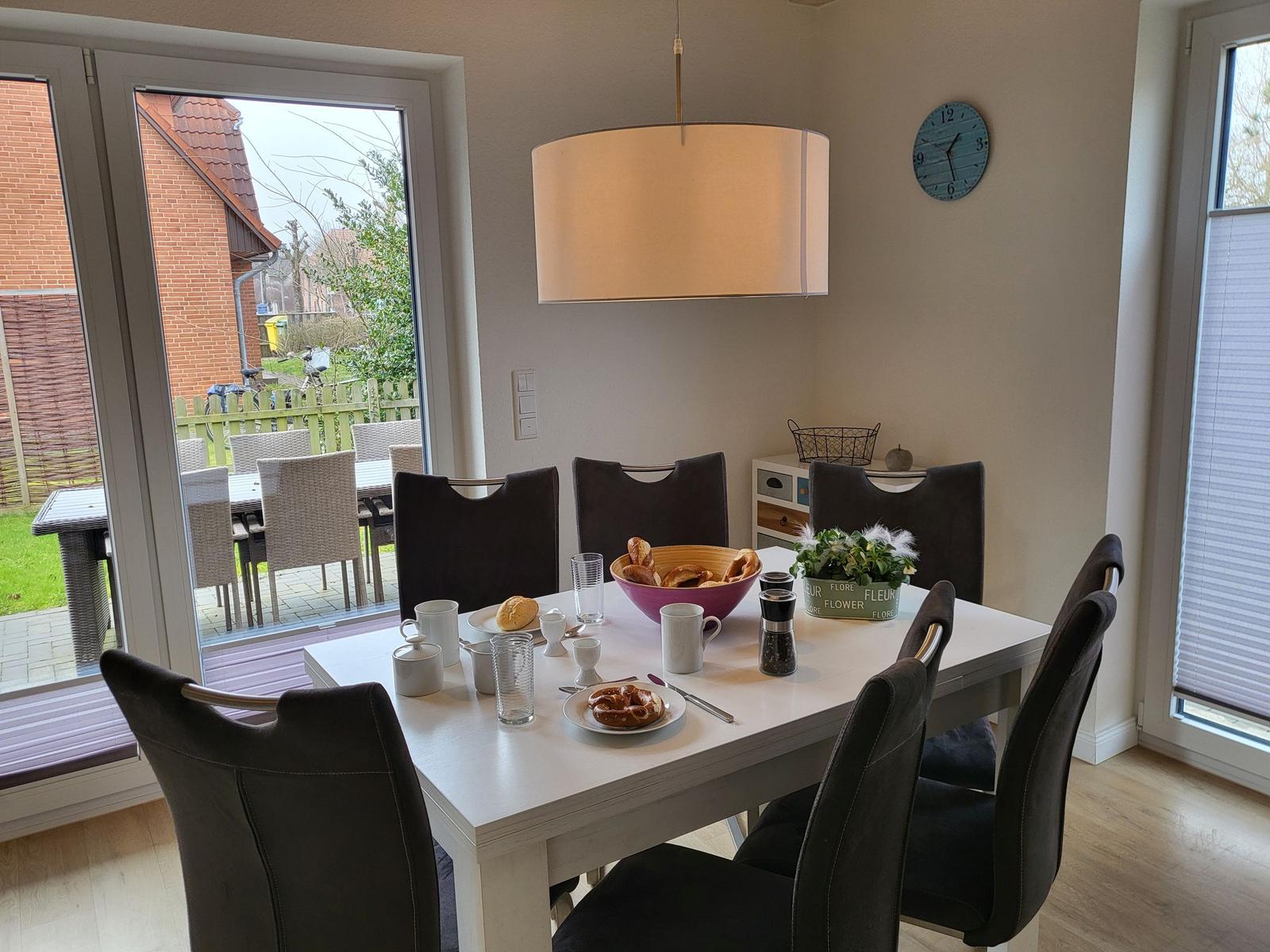 Esszimmer mit Tisch, Stühlen und Blick auf die Terrasse.